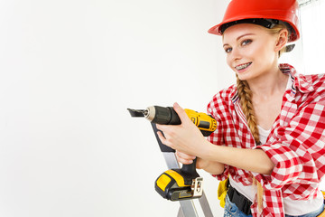 Woman using drill on ladder