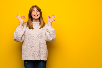 Redhead woman over yellow wall in zen pose