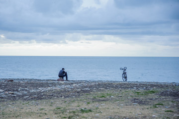 Man and bike on the beach against the backdrop of the sea and clouds