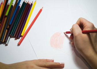 girl's hand draws a heart with color pencil