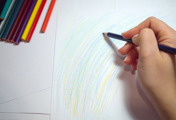 girl's hand creates an abstract drawing with colored pencils