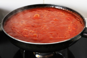 red tomato sauce cooking on fire in a pan