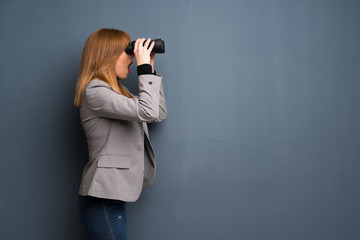 Redhead business woman and looking in the distance with binoculars