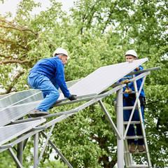 Installing of stand-alone solar photo voltaic panel system. Two workers assembling solar modules on...