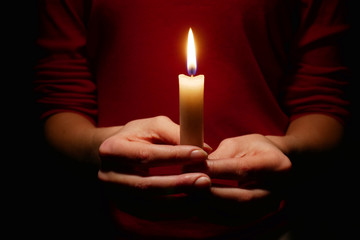 Bright candle light in the hands of the girl.  Faith in God.  Prayer with candles in hand.  Woman...