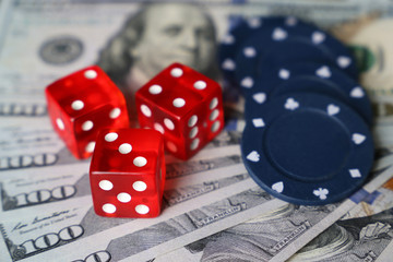 Red dice and casino gaming chips on US dollars bills. Concept of casino games, winning, gambling, luck or randomness