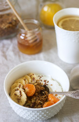 Breakfast of granola with yogurt and tea and forsythia flowers on a linen tablecloth. Rustic style.