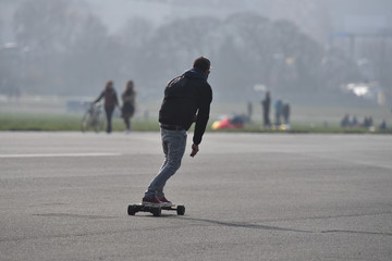 A young man on an electric skateboard drives on the airport runway of the airport Berlin-Tempelhof.