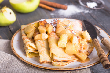 Crepes with apple filling and caramel sauce on a plate close-up, selective focus.