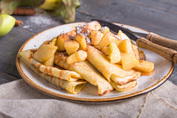 Crepes with apple filling and caramel sauce on a plate close-up, selective focus.