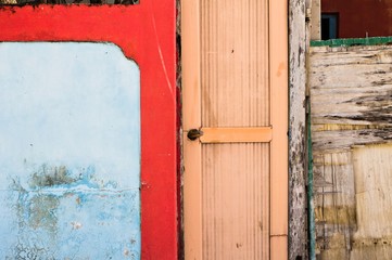 Wooden door of an abandoned house with a red and blue wall (Ar Atoll, Maldives)