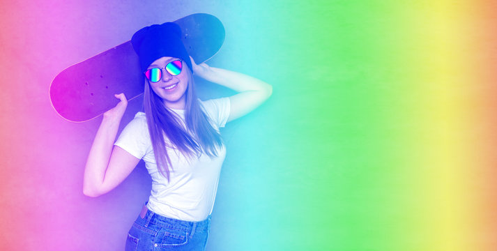 Beautiful hipster girl with skate board wearing sunglasses on a gray background long banner neon.
