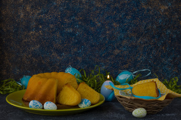 Easter bread on green plate and painted Easter eggs ion dark stone table decorated with green grass