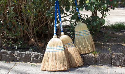 broom stick lay against the wall with green grass field in the background.