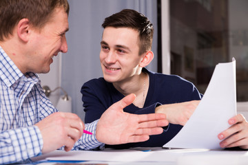 Adult male with his son are looking in documents