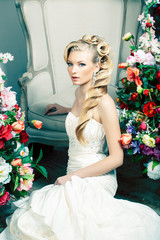 beauty emotional blond bride in luxury interior dreaming, crazy complicate hairstyle, many flowers