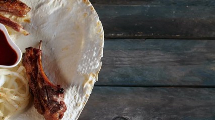 Lamb loin shish kebab with onions on pita close up. Rotates on a wooden background. Top view with the copy space for your text.
