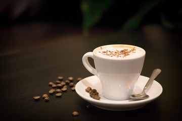 Coffee cup with coffee beans on black table.