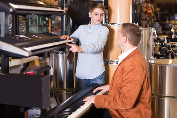 Smiling boy and father deciding on synthesizer