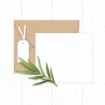 Flat lay top view elegant white composition paper brown kraft envelope tag and tarragon leaf on wooden background