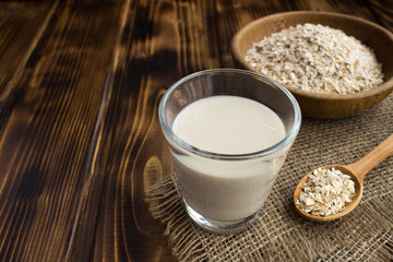 Oat milk in the glass on the rustic wooden background.Healthy drink.