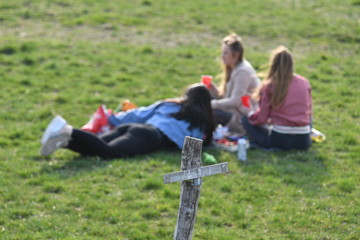 A blurred group of female students on green meadow in Berlin-Tempelhof behind a wooden cross. 