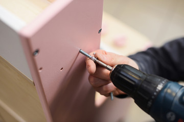 Carpenter working on play furniture. Tightening screws with screwdriver