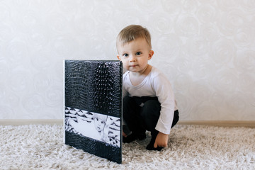 Cute baby sitting next to his big stylish photo album