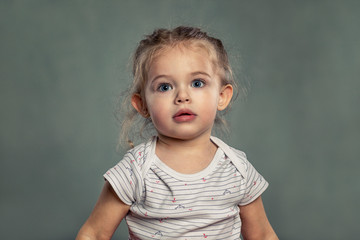 Naklejka premium Cute little girl with big blue eyes. Gray background.