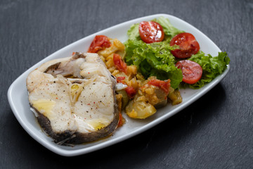 boiled fish with vegetables and fresh salad on white dish