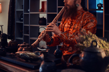 Chinese tea ceremony. Caucasian master in kimono making natural tea in the dark room with a wooden interior. Tradition, health, harmony