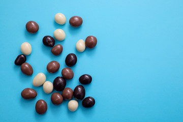 close up of chocolate egg and candy drops on blue background
