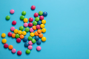 close up of chocolate egg and candy drops on blue background