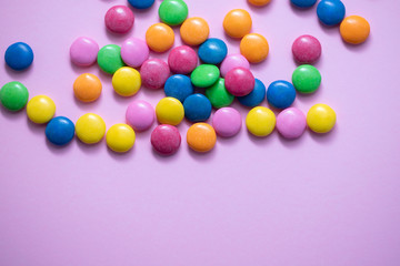 close up of chocolate egg and candy drops on pink background