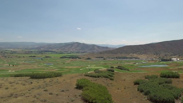 golf course during dry summer with brown patches soldier hollow aerial drone. A drone flies over a green golf course in a mountain valley. You can see some brown dry patches in this mountain desert.