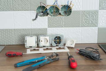 Preparing to install an electrical outlet. Closeup of professional electrician tools and electrical outlets. Renovation and construction in kitchen.
