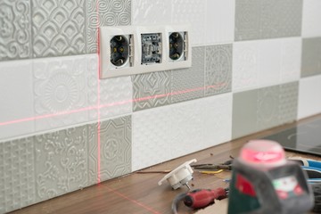 Electrician using infrared laser level to install electrical outlets. Renovation and construction...