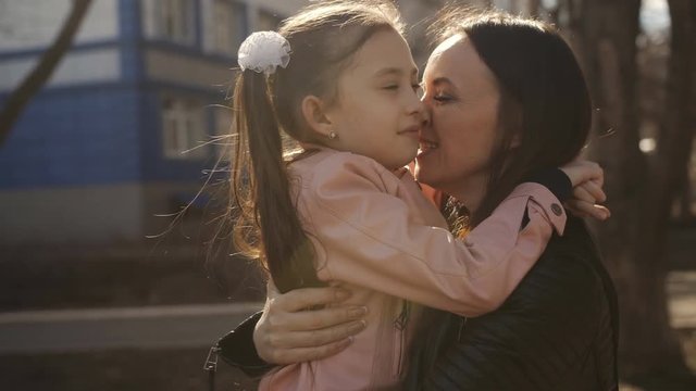 Mother hugging and kissing a little daughter after school.