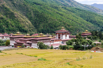 Fototapeta na wymiar Tashichho Dzong, also known as Dzong of Thimphu, in Thimphu the capital of Bhutan. Paddy test area in the foreground.