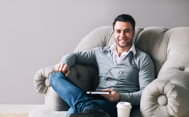 Handsome man sitting in an armchair looks away