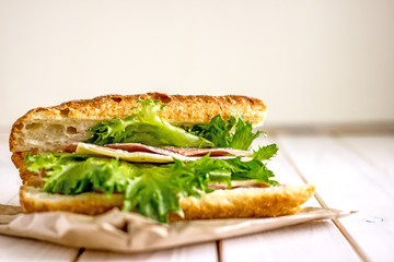 Closed sandwich with greens, ham and cheese. Close-up, copy space
