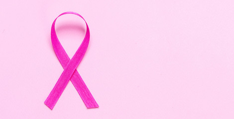 Pink color ribbon against pastel pink background. Breast cancer awareness,