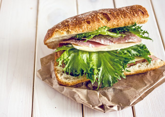 Closed sandwich with greens, ham and cheese. Close-up, copy space