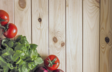 Culinary background, wooden light surface on it red tomatoes, onions and fresh greens, top view, copy space, texture