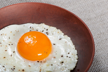 Fried egg on a clay plate, breakfast food.