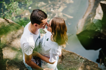 Young gentle couple hugging on stone near the lake. stand against the background of the rocks. Top view. Nature. upper half. looking at each other. Side view. Close up. Lovers.