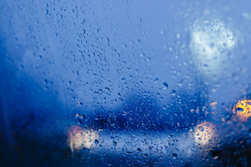 Night city lights through windshield abstract background water drop on the glass lights and rain