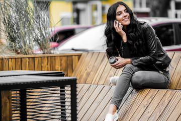 Happy latin woman with smartphone or laptop in city centre