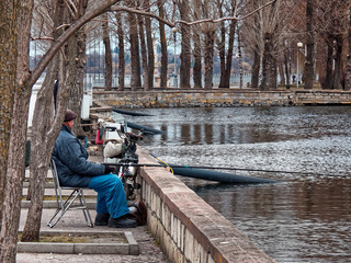 Old fisherman with a bicycle on a city pond