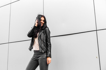 young latin woman walking with happy emotion on grey wall